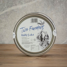 Load image into Gallery viewer, A round metal tin of Two Farmers' lightly salted ham, standing upright on a wooden surface against a textured gray background.